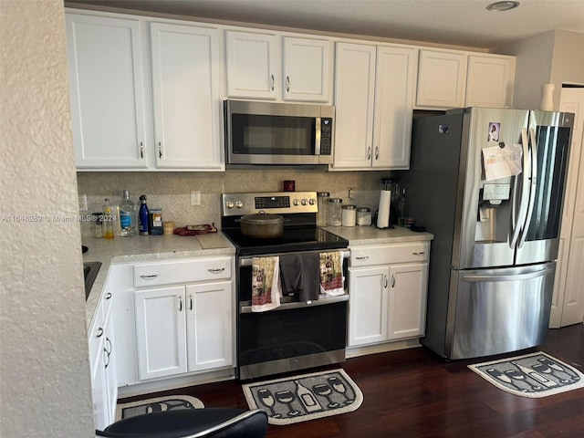 kitchen with stainless steel appliances, dark wood-type flooring, white cabinets, and light countertops