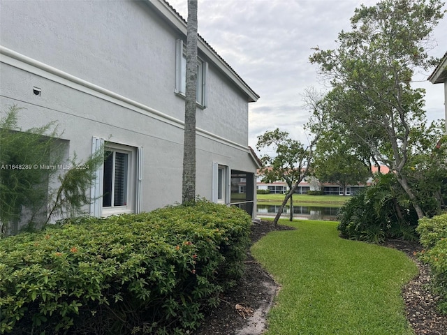 view of home's exterior featuring stucco siding, a lawn, and a water view