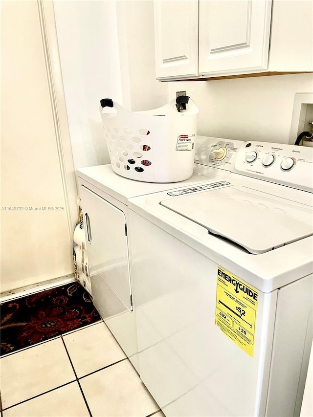 laundry room with cabinets, light tile patterned floors, and washing machine and clothes dryer