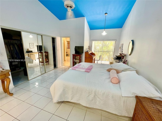 tiled bedroom featuring ensuite bathroom, high vaulted ceiling, and a closet