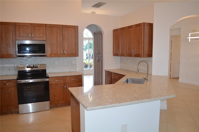 kitchen with light tile patterned flooring, sink, appliances with stainless steel finishes, and tasteful backsplash