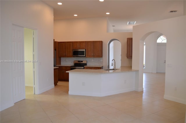 kitchen with appliances with stainless steel finishes, tasteful backsplash, sink, and light tile patterned flooring