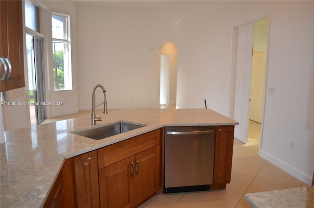 kitchen with light stone countertops, light tile patterned floors, stainless steel dishwasher, kitchen peninsula, and sink