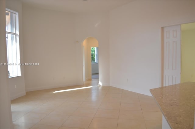 empty room featuring a high ceiling and light tile patterned floors