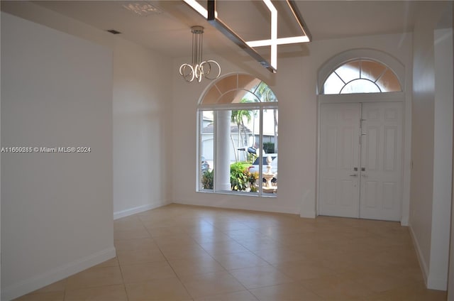 foyer entrance with light tile patterned floors, plenty of natural light, and an inviting chandelier