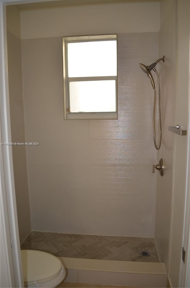 bathroom featuring tiled shower and toilet