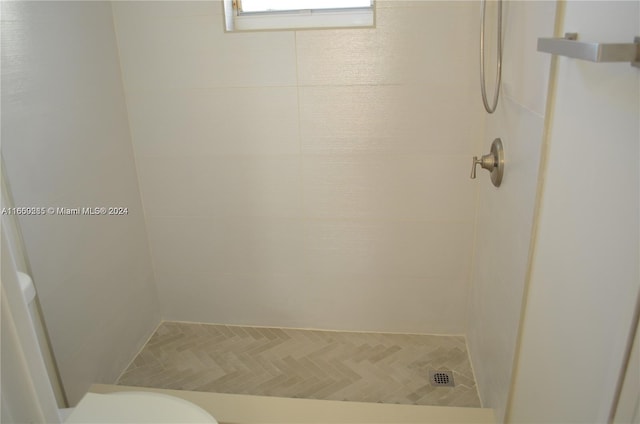 bathroom featuring tiled shower and toilet