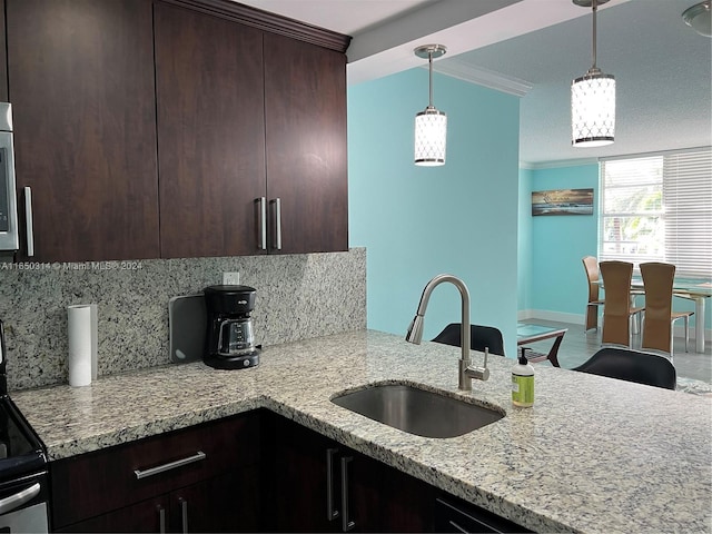 kitchen with pendant lighting, backsplash, ornamental molding, sink, and light stone counters