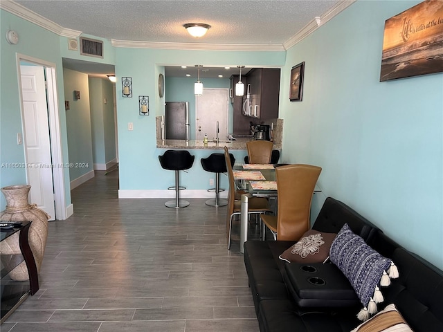 living room featuring a textured ceiling, dark wood-type flooring, ornamental molding, and sink