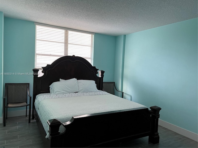 bedroom featuring a textured ceiling and dark hardwood / wood-style flooring