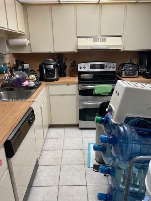 kitchen with dishwasher, stainless steel electric range, sink, and light tile patterned flooring