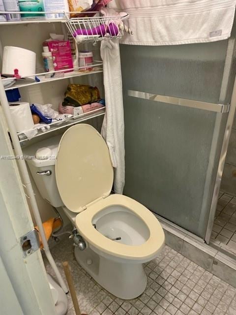 bathroom featuring toilet, a shower, and tile patterned floors