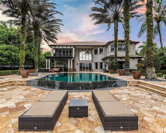 pool at dusk featuring a pergola and a patio area