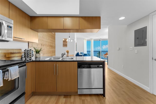 kitchen featuring appliances with stainless steel finishes, electric panel, light hardwood / wood-style floors, sink, and pendant lighting