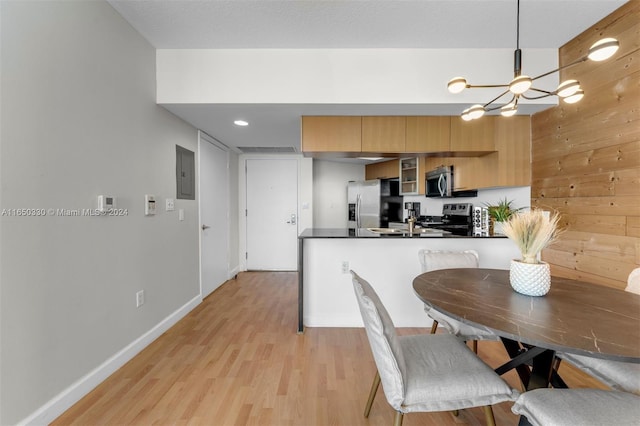 kitchen featuring decorative light fixtures, light hardwood / wood-style flooring, a notable chandelier, stainless steel appliances, and kitchen peninsula