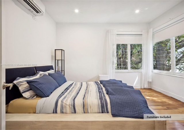 bedroom with a wall unit AC and hardwood / wood-style floors