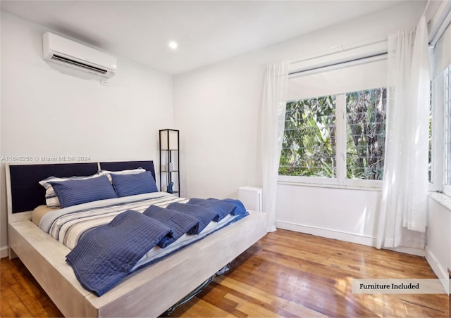 bedroom with a wall unit AC and wood-type flooring