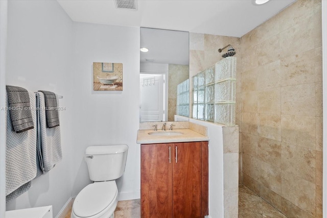 bathroom featuring tiled shower, vanity, and toilet