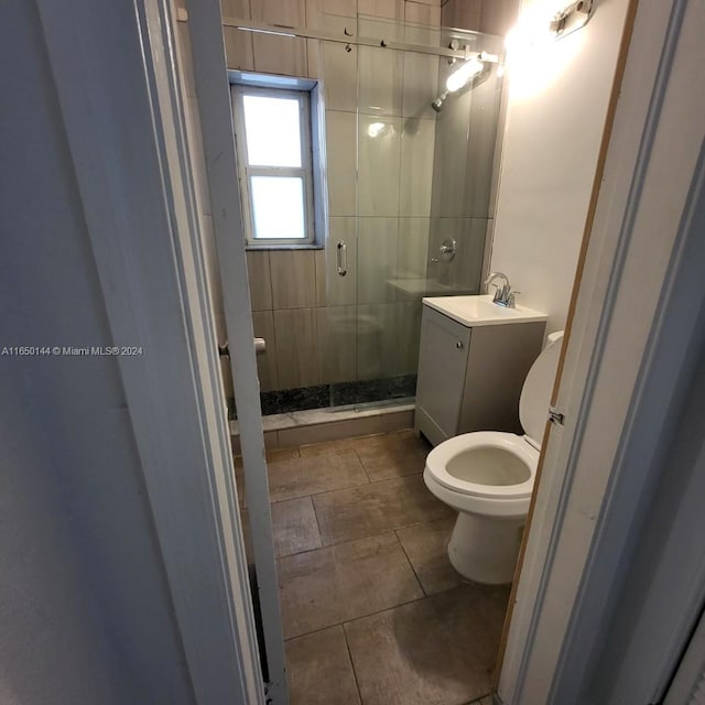 bathroom featuring walk in shower, toilet, vanity, and tile patterned flooring