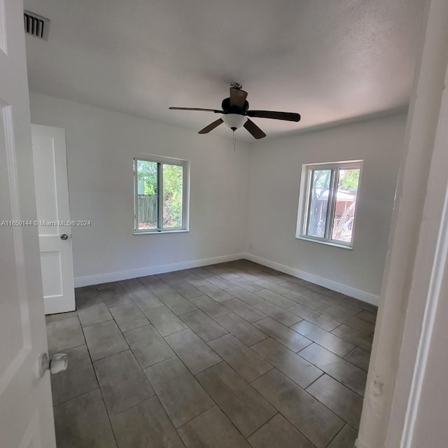 tiled empty room featuring ceiling fan and a healthy amount of sunlight