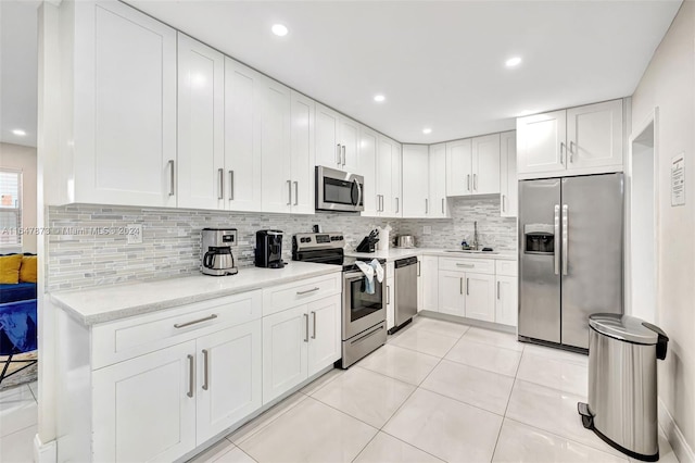 kitchen featuring appliances with stainless steel finishes, light tile patterned floors, sink, and decorative backsplash