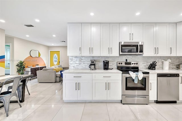 kitchen featuring white cabinets, backsplash, stainless steel appliances, and light tile patterned flooring