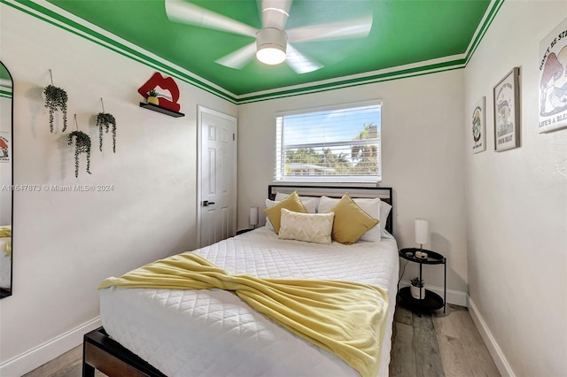 bedroom with crown molding, ceiling fan, and dark hardwood / wood-style flooring