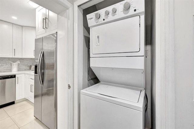 laundry room featuring stacked washer and dryer and light tile patterned flooring