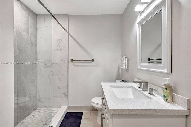 bathroom with tile patterned flooring, toilet, a tile shower, and vanity