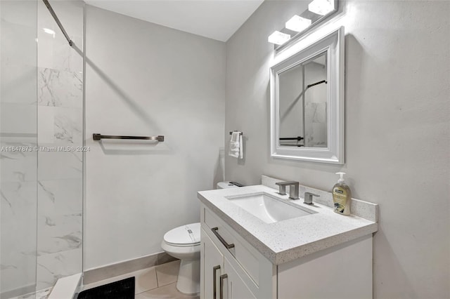 bathroom with vanity, toilet, a tile shower, and tile patterned flooring