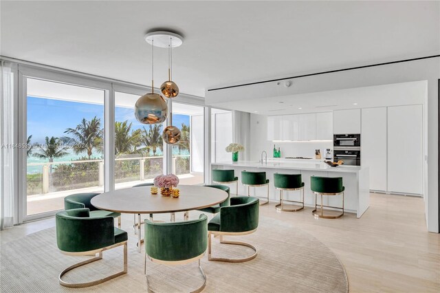 dining room featuring floor to ceiling windows, sink, and light hardwood / wood-style flooring