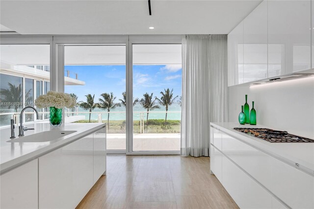 kitchen featuring a water view, sink, white cabinets, and light hardwood / wood-style floors