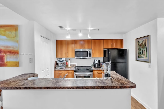 kitchen with light hardwood / wood-style floors, stainless steel appliances, track lighting, and sink