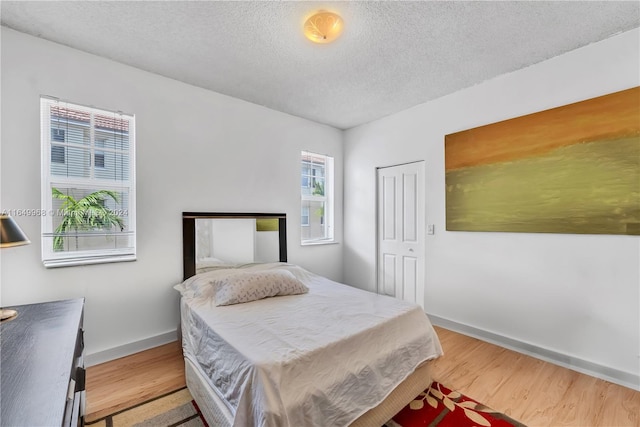 bedroom with a closet, a textured ceiling, and wood-type flooring