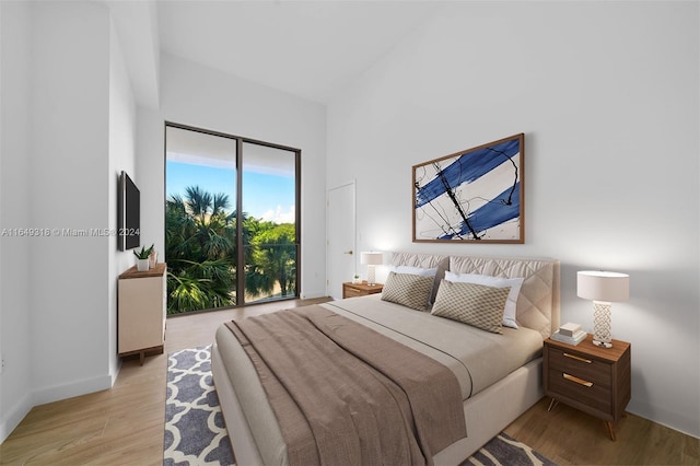 bedroom featuring access to exterior, high vaulted ceiling, and light hardwood / wood-style floors