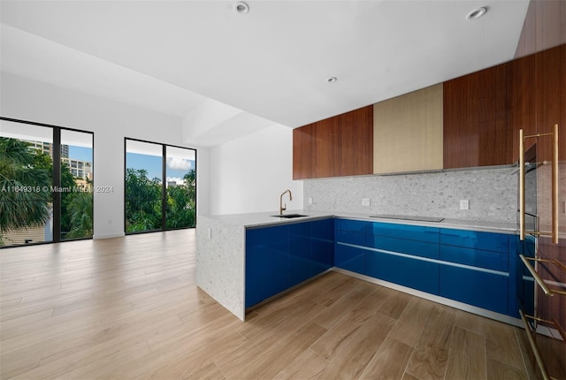 kitchen featuring light hardwood / wood-style floors, sink, black electric cooktop, kitchen peninsula, and tasteful backsplash