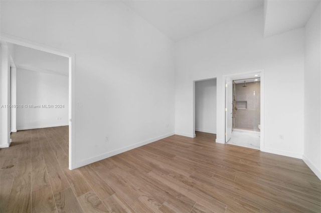 spare room featuring light wood-type flooring and high vaulted ceiling