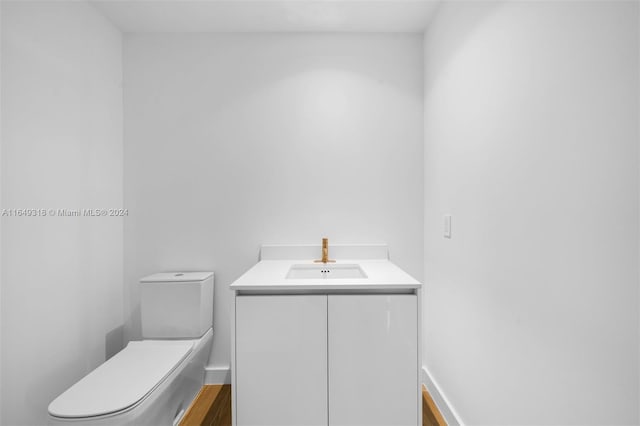 bathroom with vanity, toilet, and hardwood / wood-style flooring