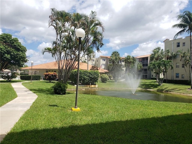 view of property's community with a water view and a lawn