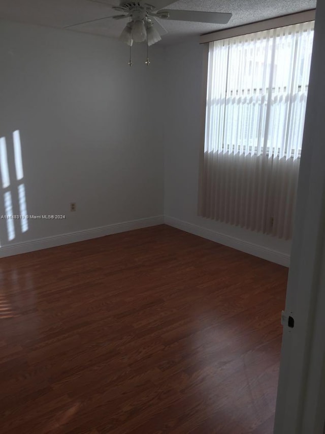 unfurnished room featuring dark wood-type flooring and ceiling fan