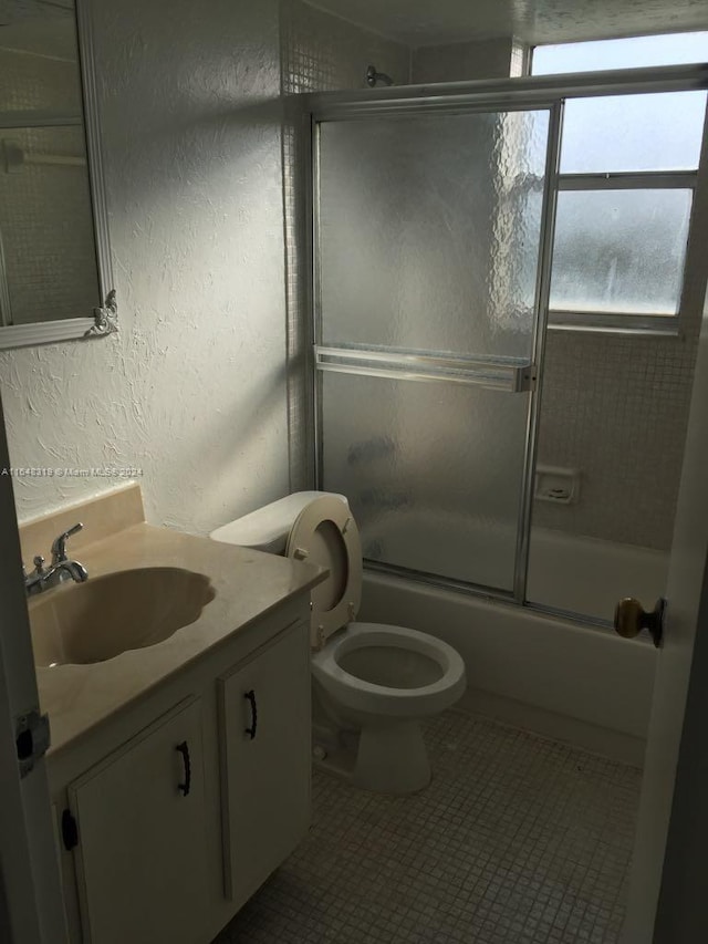 full bathroom with tile patterned flooring, vanity, toilet, and combined bath / shower with glass door