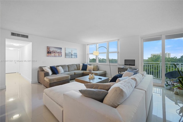 living area with visible vents, light tile patterned floors, a wealth of natural light, and floor to ceiling windows