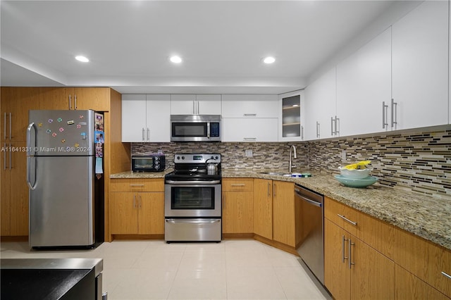 kitchen featuring appliances with stainless steel finishes, brown cabinetry, and white cabinetry