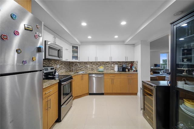 kitchen featuring wine cooler, appliances with stainless steel finishes, decorative backsplash, light stone counters, and white cabinets