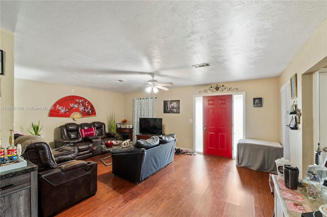 living room with ceiling fan, dark hardwood / wood-style floors, and a textured ceiling