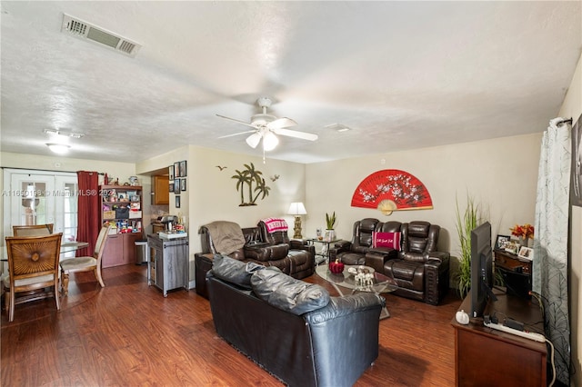 living room featuring a textured ceiling, dark wood-type flooring, and ceiling fan