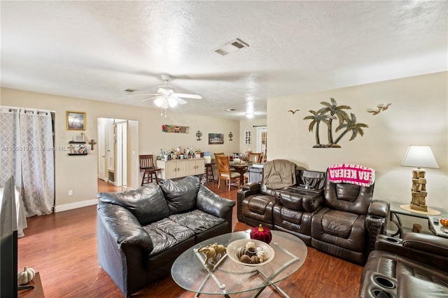 living room with wood-type flooring, a textured ceiling, and ceiling fan