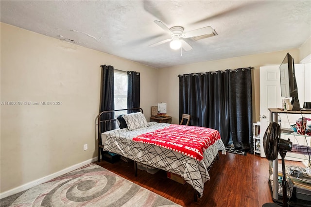 bedroom with ceiling fan, dark hardwood / wood-style flooring, and a textured ceiling