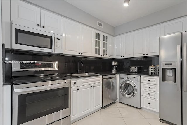 kitchen featuring backsplash, stainless steel appliances, sink, washer / dryer, and white cabinets