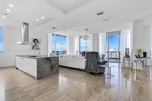 kitchen featuring a chandelier, light tile patterned floors, sink, island exhaust hood, and expansive windows